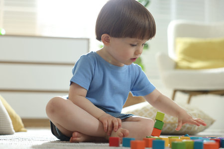 Cute little child playing with colorful cubes at home