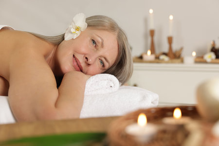 Senior woman relaxing on massage couch in spa salonの写真素材