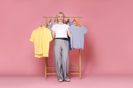 Fashion stylist and rack with clothes on pink backgroundの写真素材