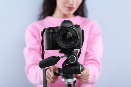 Woman with professional video camera on light grey background, selective focusの写真素材