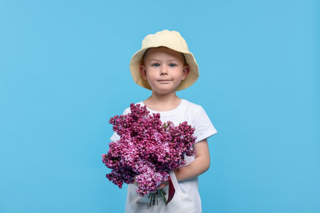 Little boy with bouquet of lilac flowers on light blue backgroundの写真素材