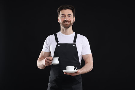 Portrait of smiling barista making coffee on black backgroundの写真素材