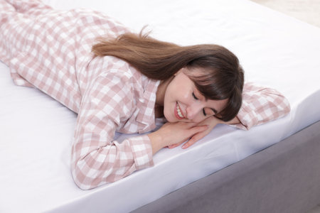 Beautiful woman lying on soft mattress at homeの写真素材