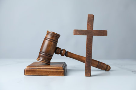 Judge's gavel and wooden cross on white marble tableの写真素材