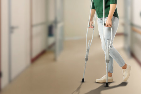 Woman with axillary crutches in hospital, closeup. Space for textの写真素材