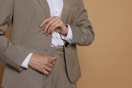 Woman in suit on beige background, closeup. Space for textの写真素材