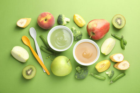 Baby food. Tasty puree in bowls and ingredients on green background, flat layの写真素材