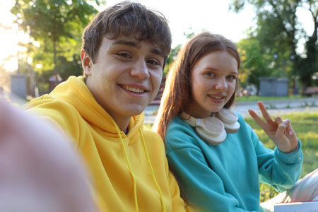 Teenage girl and boy taking selfie together in park