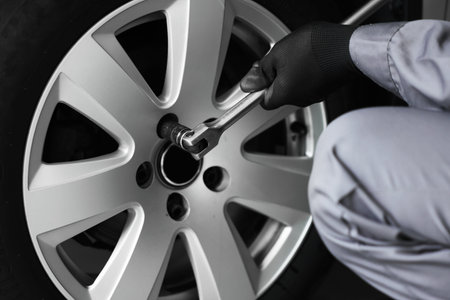 Mechanic changing tire at car service, closeup
