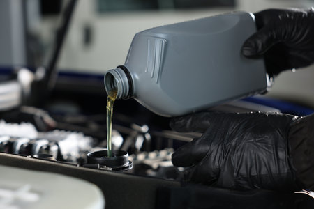 Worker pouring motor oil from canister into car engine, closeupの写真素材