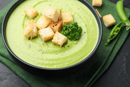 Tasty pea cream soup with croutons and broccoli served on black table, closeupの写真素材