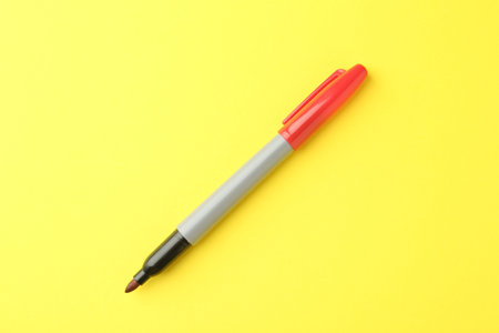 One red marker on yellow background, top viewの写真素材