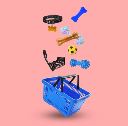 Different products for pets falling into shopping basket on pink backgroundの写真素材