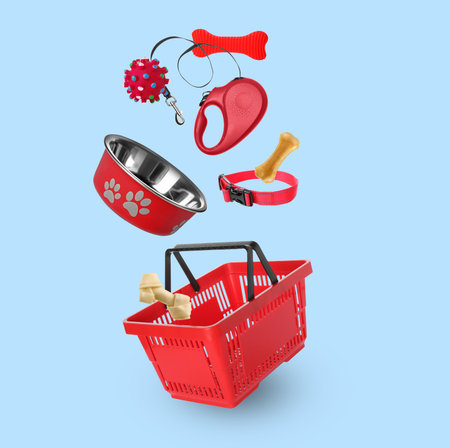 Different products for pets falling into shopping basket on light blue backgroundの写真素材