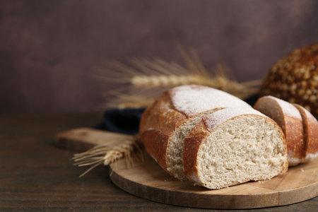 Fresh cut bread and spikes on wooden table, closeup. Space for textの写真素材