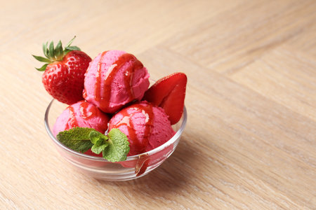 Refreshing sorbet with syrup, strawberries and mint in bowl on wooden table, closeup. Space for textの写真素材