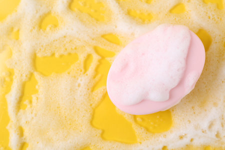 Soap bar with foam on yellow background, top view. Space for textの写真素材