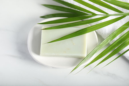 Soap bar, towel and palm leaf on white marble table, above viewの写真素材