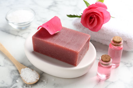 Soap bars, cosmetic products, towel and beautiful rose on white marble table, closeupの写真素材