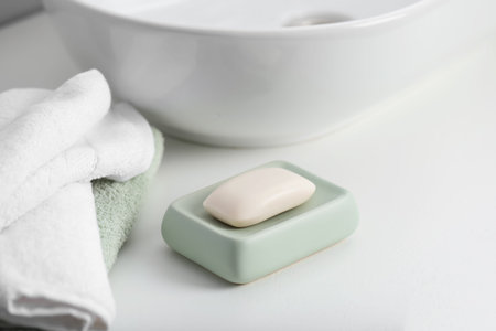 Soap bar and towels on white countertop indoors, closeup