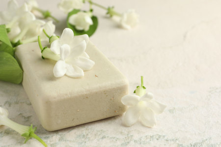 Bar of soap and jasmine flowers on light table, closeup. Space for textの写真素材