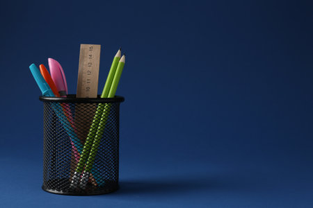 Different stationery in pen holder on dark blue background. Space for textの写真素材