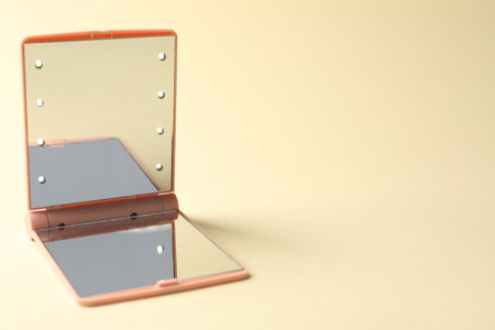Open pocket mirror on beige background, closeup. Space for textの写真素材