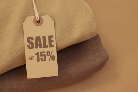 Sale tag and clothes on pale brown background, closeupの写真素材