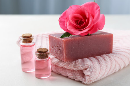 Aromatic soap bar, rose, towel and cosmetic products on light tableの写真素材
