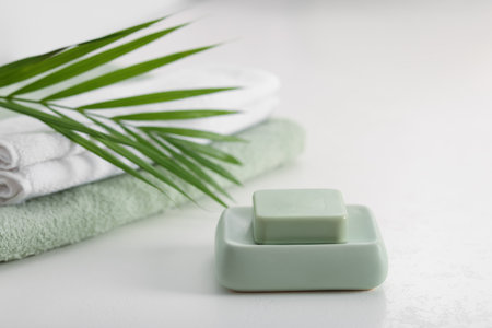 Soap bar, towels and palm leaf on white table, closeupの写真素材