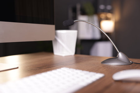 Microphone and computer on wooden desk indoors