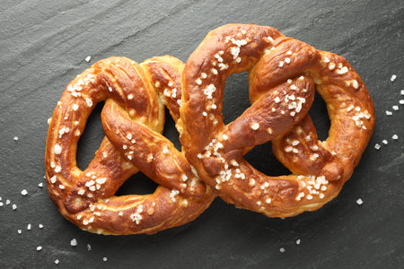 Tasty pretzels with salt on black table, flat lay
