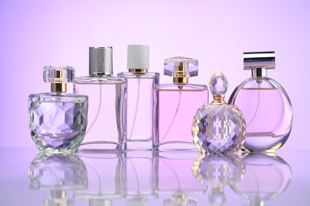 Bottles of perfume on mirror surface against pale violet gradient backgroundの写真素材
