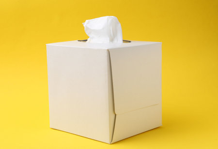 Box with paper handkerchiefs on yellow backgroundの写真素材