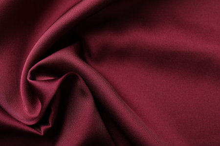 Crumpled burgundy silk fabric as background, top view