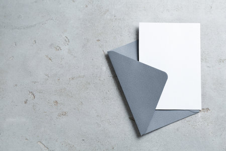 Blank invitation card and envelope on light grey table, top view. Space for designの写真素材