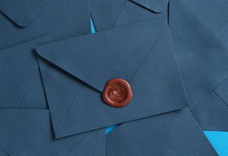 Beautiful invitation envelopes on light blue background, flat lay