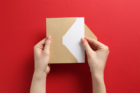 Woman holding envelope with blank invitation card on red background, top viewの写真素材