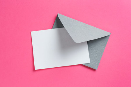 Blank invitation card and envelope on pink background, top view. Space for design