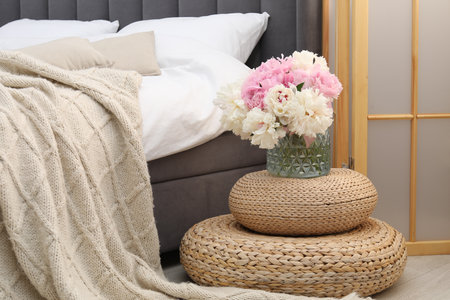 Side table with flowers near bed indoorsの写真素材