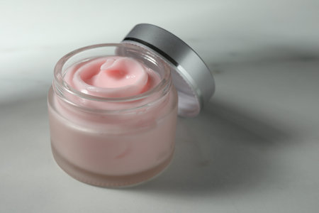 Jar of moisturizing body cream on white table, closeup