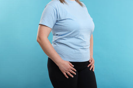 Weight loss. Plus size woman on light blue background, closeupの写真素材