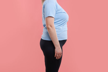 Weight loss. Plus size woman on pink background, closeupの写真素材