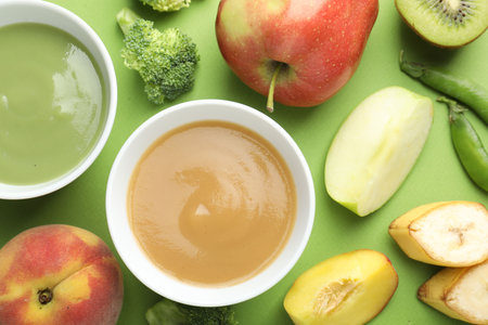 Baby food. Tasty puree in bowls and ingredients on green background, flat layの写真素材