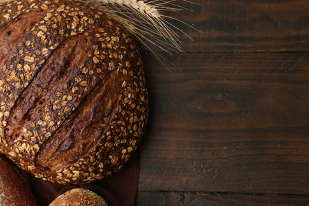 Freshly baked loaves of bread and spikes on wooden table, flat lay. Space for textの写真素材