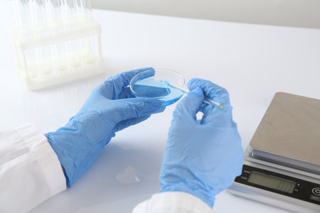 Scientist working with sample near scales at white table, closeupの写真素材