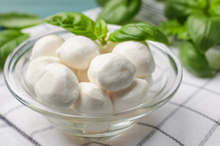Mozzarella cheese balls and basil on blue table, closeupの写真素材
