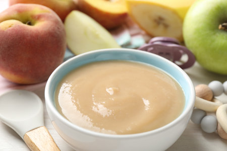 Baby food. Tasty puree in bowl, different ingredients, teether and pacifier on table, closeupの写真素材