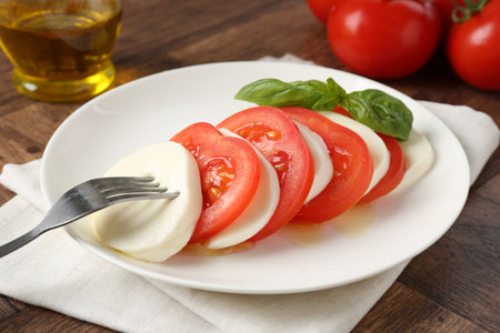 Tasty mozzarella, tomatoes, oil and basil on wooden table, closeupの写真素材