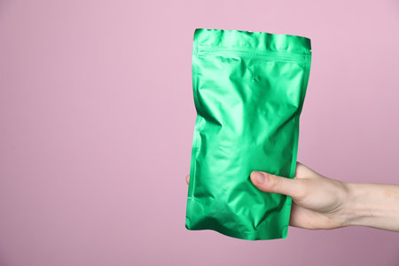 Woman with zipper stand-up pouch on pink background, closeup. Mockup for designの写真素材